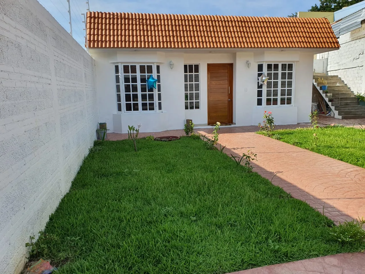 Casa de una planta con cubierta de teja y jardín con andador