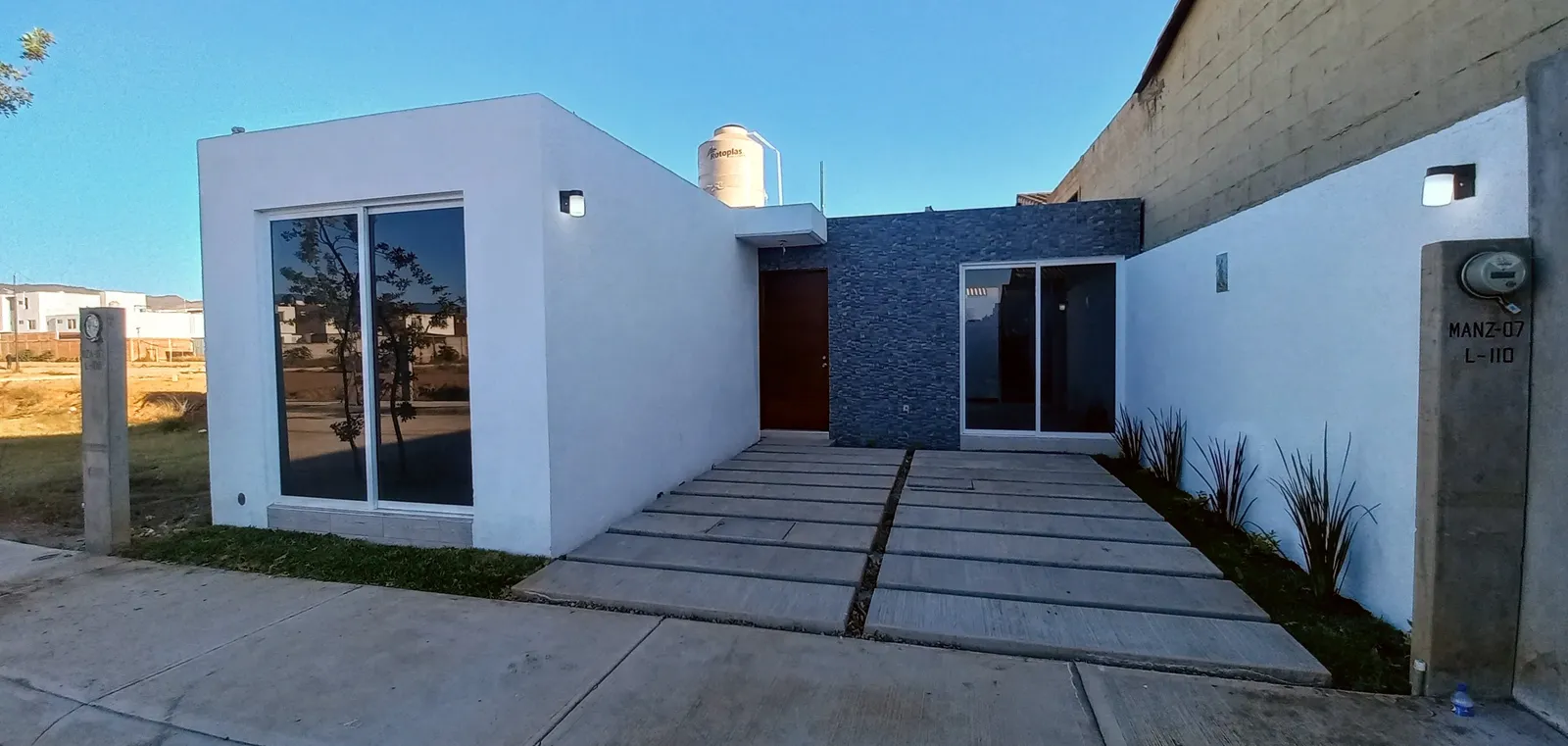 Casa de una planta con muro de piedra y acceso de concreto