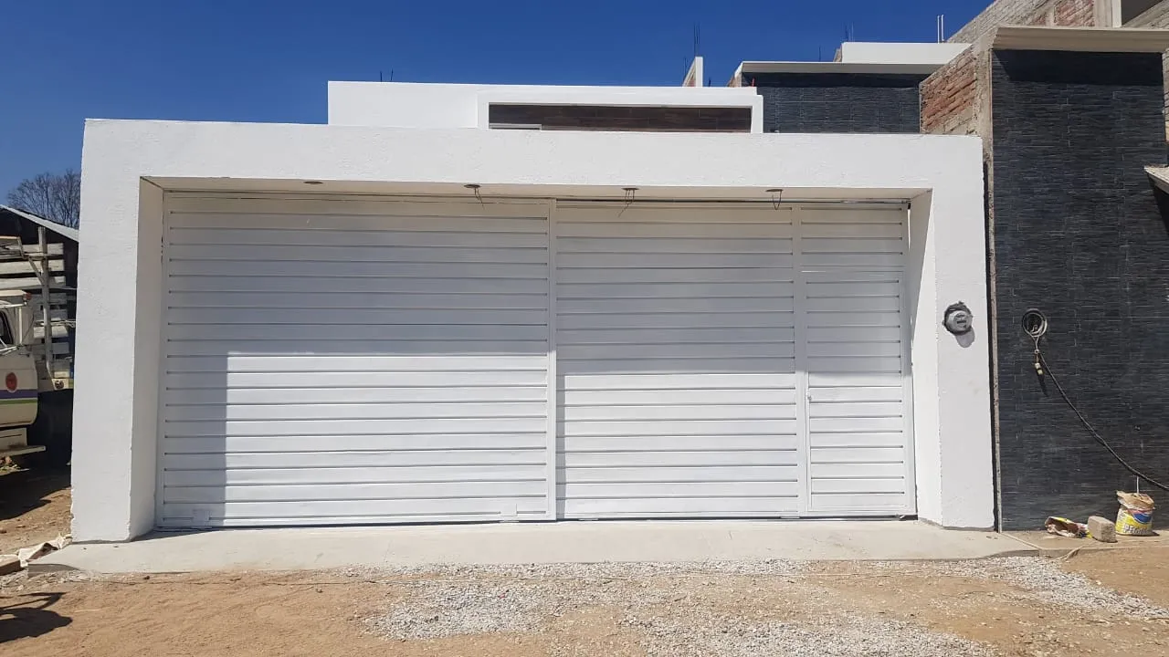 Cerramiento de fachada antes de acabados, con portón de lamas metálicas