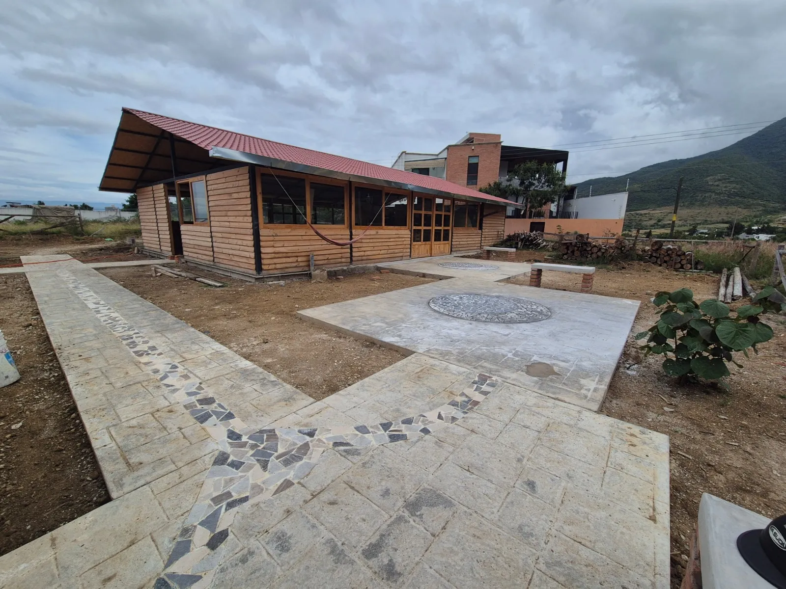 Cabaña de madera con cubierta a dos aguas y patio de piedra recién colocado
