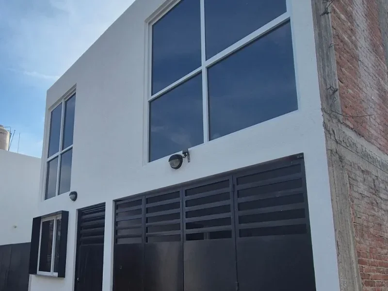 Casa de dos plantas con portón de lamas metálicas negro