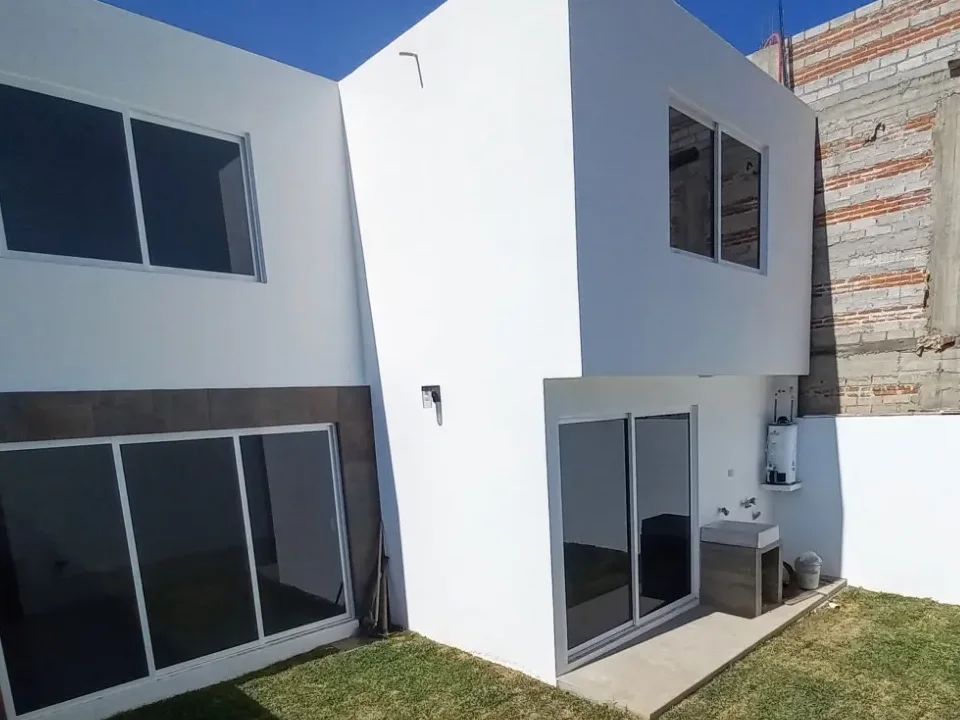 Patio trasero terminado, con césped y ventanales corredizos